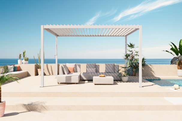 White louvered aluminium pergola with adjustable roof slats overlooking a modern patio and coastal outdoor living area