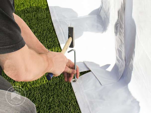 Ground anchor being installed through the floor skirt of a high peak frame tent