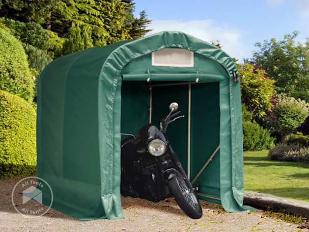 Green portable motorcycle garage with steel frame and tarpaulin cover, housing a black motorbike in a garden setting