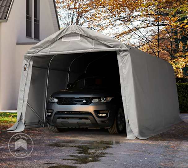 Portable garage with grey tarpaulin and steel frame sheltering a black SUV on a residential driveway in autumn